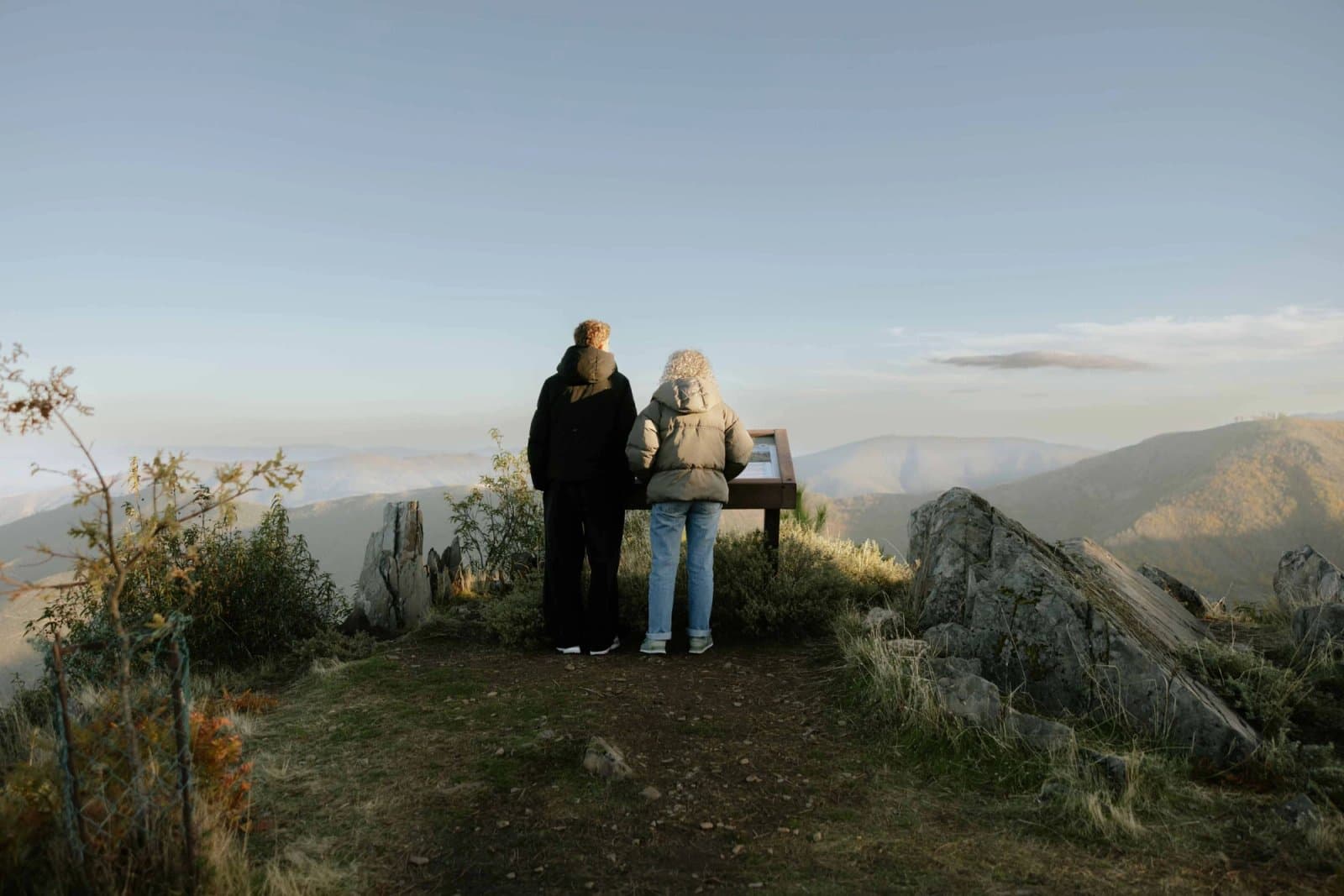Duas pessoas a ler conteúdos de mesa interpretativa ICNF em plástico reciclado na Serra da Estrela.